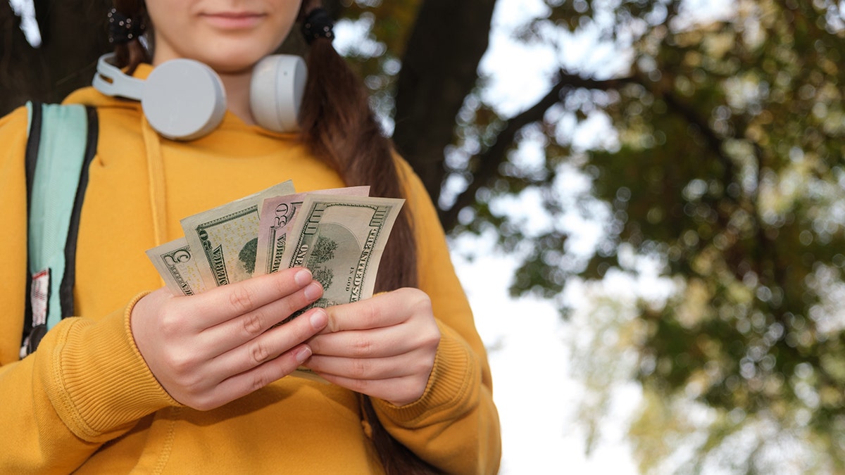 A little girl holds money from a parent